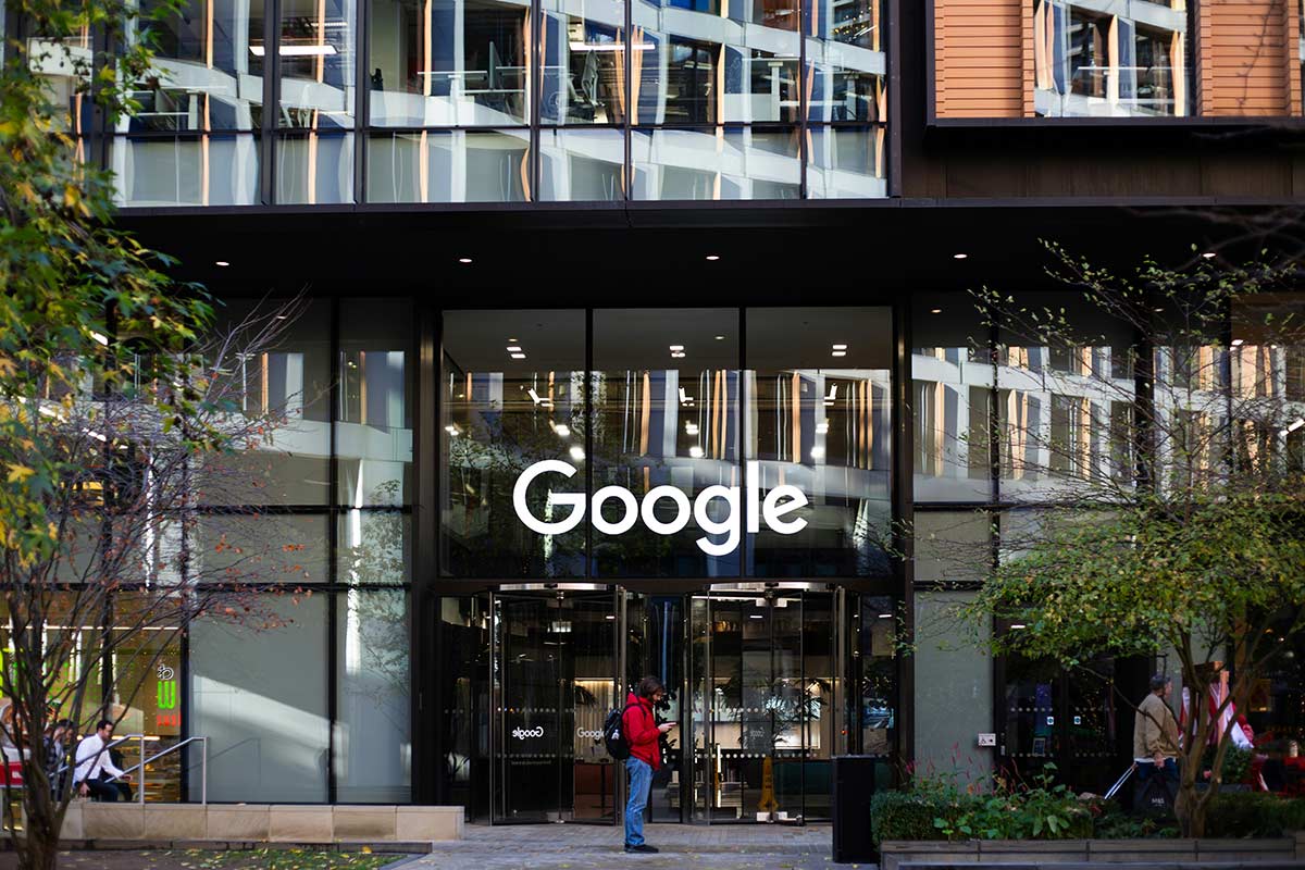 Fachada de vidro do edifício da empresa Google com o logotipo centralizado, representando as diretrizes oficiais de publicidade e a governança de IA.