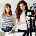 Duas influenciadoras digitais gravando vídeo em estúdio de moda para campanha de marca.