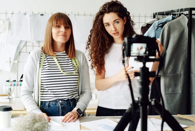 Duas influenciadoras digitais gravando vídeo em estúdio de moda para campanha de marca.