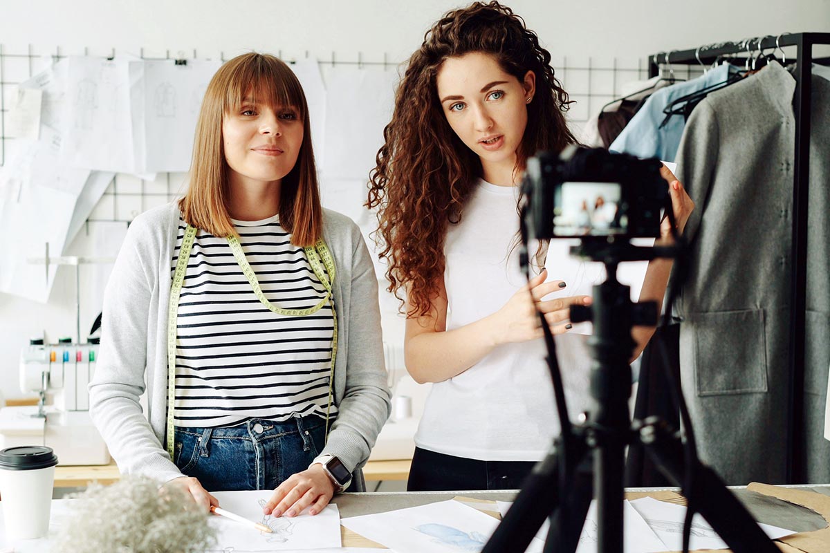 Duas influenciadoras digitais gravando vídeo em estúdio de moda para campanha de marca.