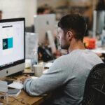 Profissional de web design trabalhando na criação e otimização do layout de um site em seu computador.
