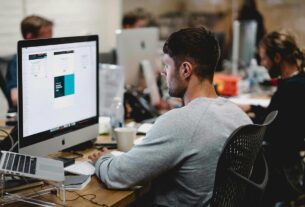 Profissional de web design trabalhando na criação e otimização do layout de um site em seu computador.